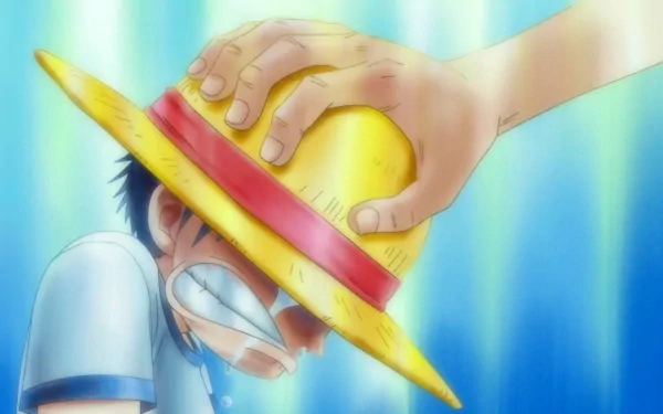 HD desktop wallpaper featuring an emotional scene from the anime One Piece, showing a hand placing a yellow straw hat on the head of a crying character with a blue background.